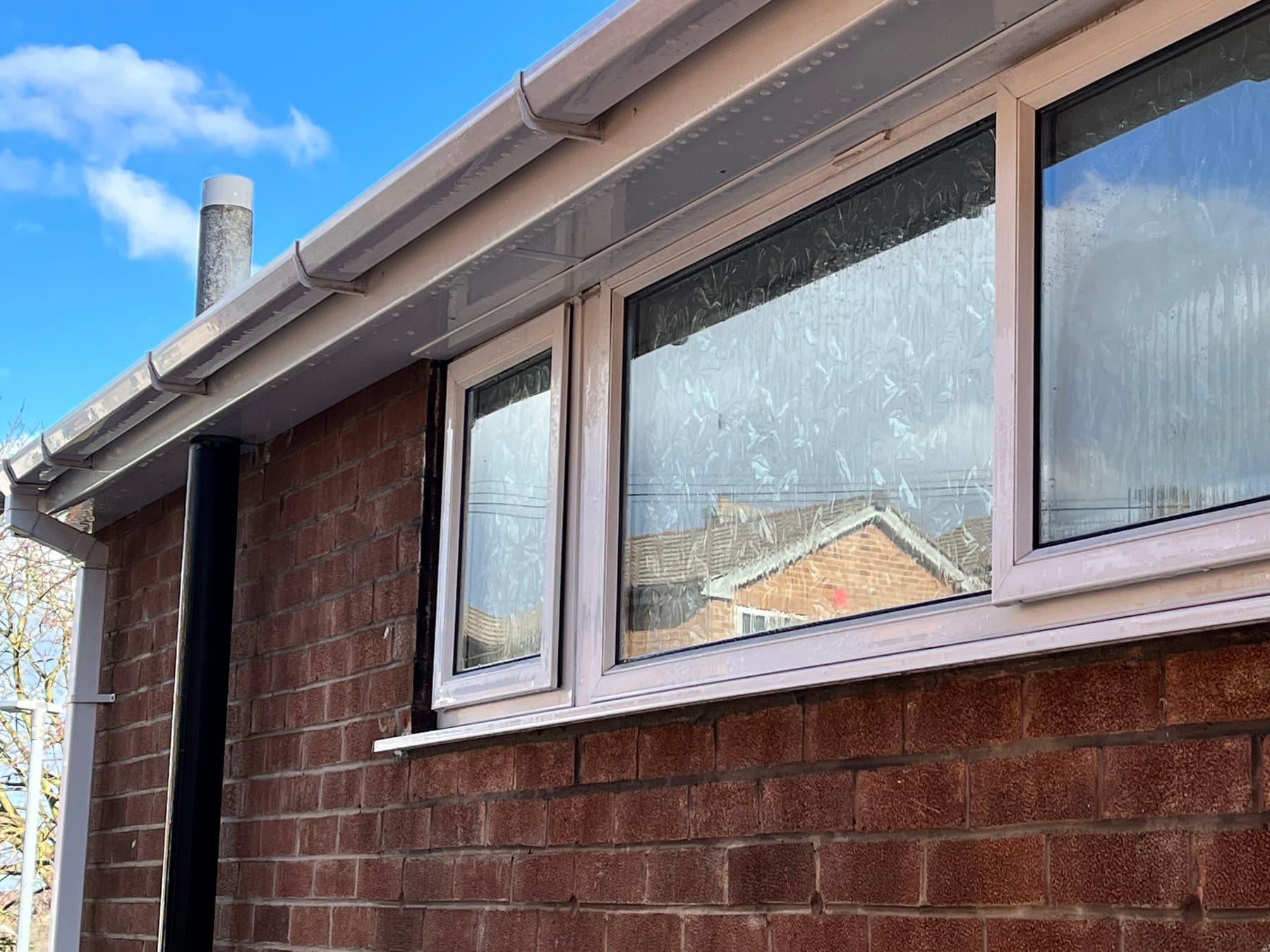 The same bungalow roofline after cleaning — fascia and soffit back to bright white