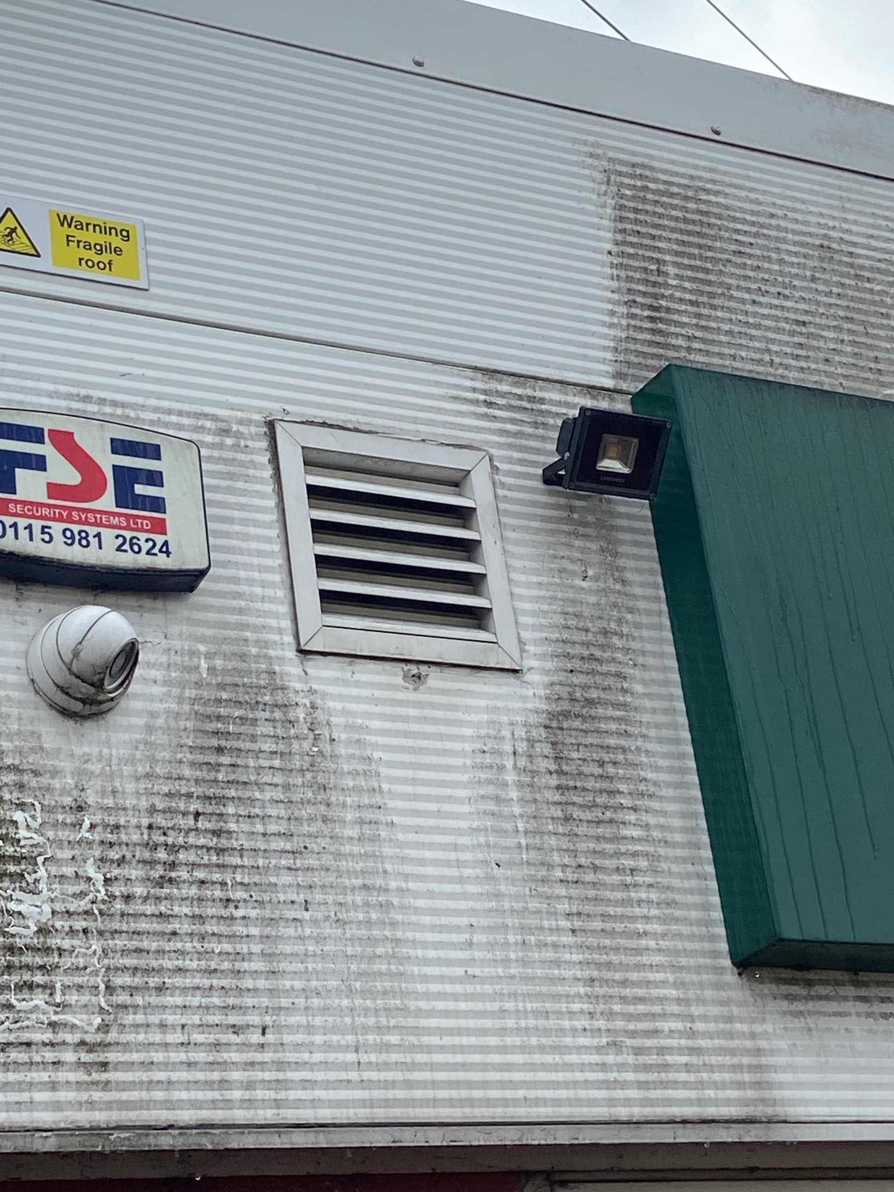 Commercial unit cladding black-streaked with algae and dirt before cleaning