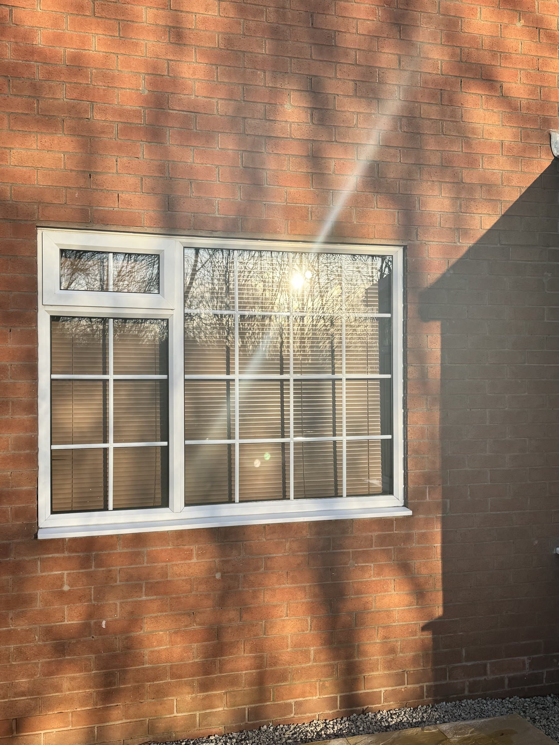 Georgian-bar uPVC window cleaned to a clear finish in a red-brick wall