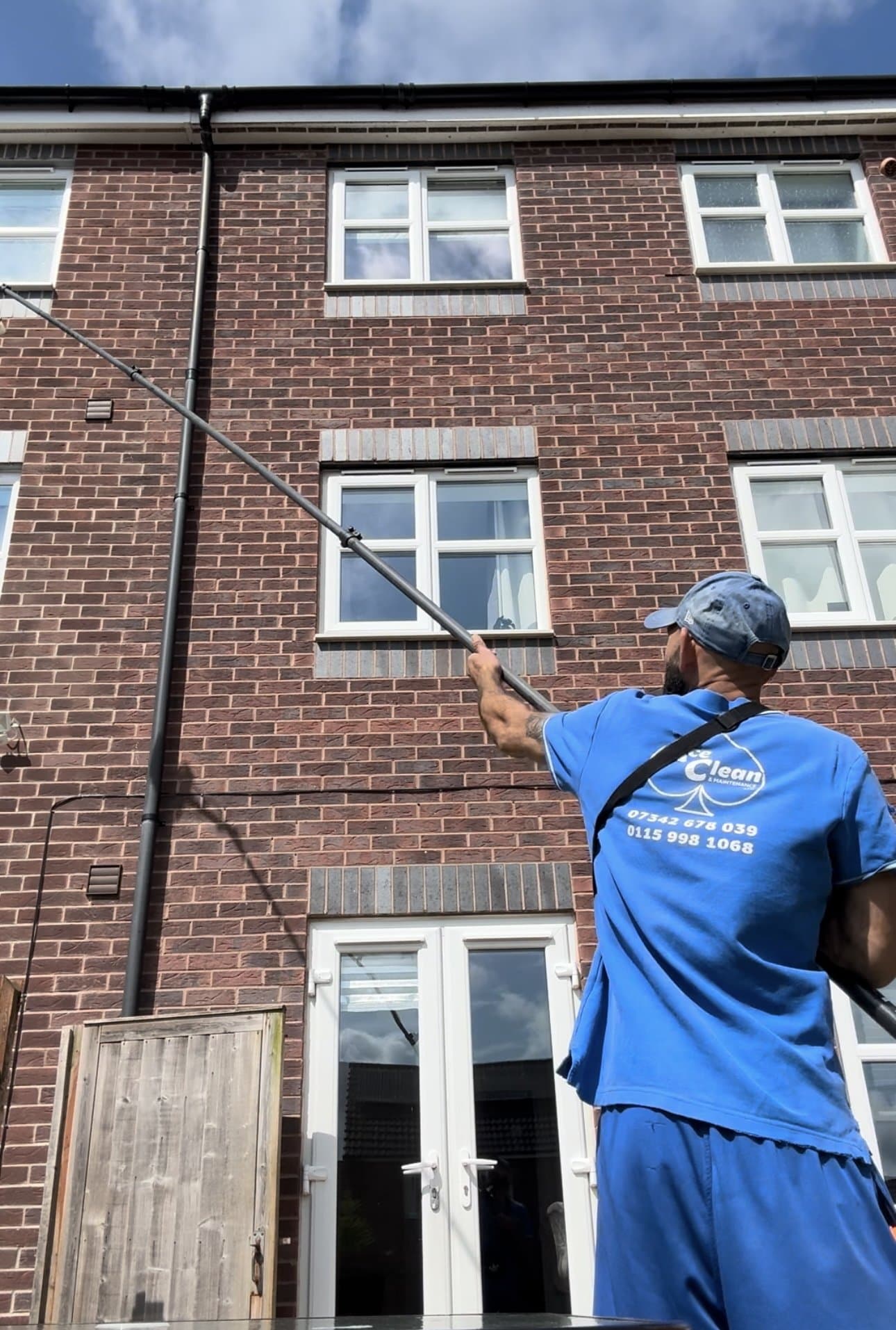 Operator reaching the upper windows of a townhouse from the ground with a water-fed pole