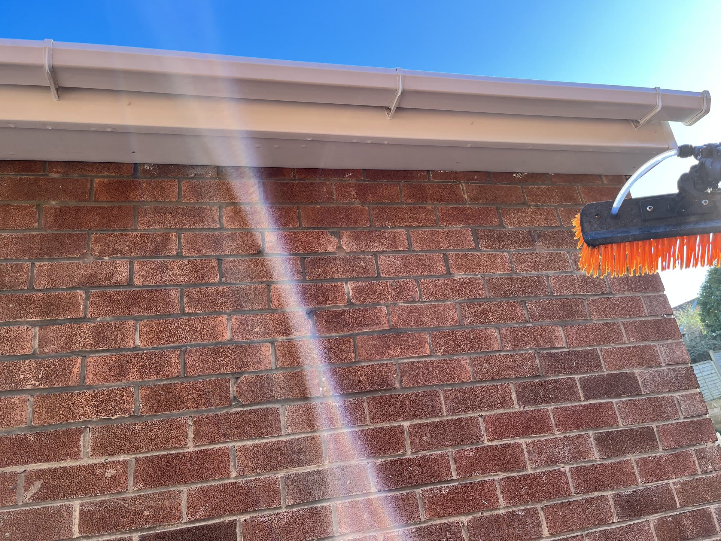 Water-fed pole cleaning a cream uPVC fascia and gutter