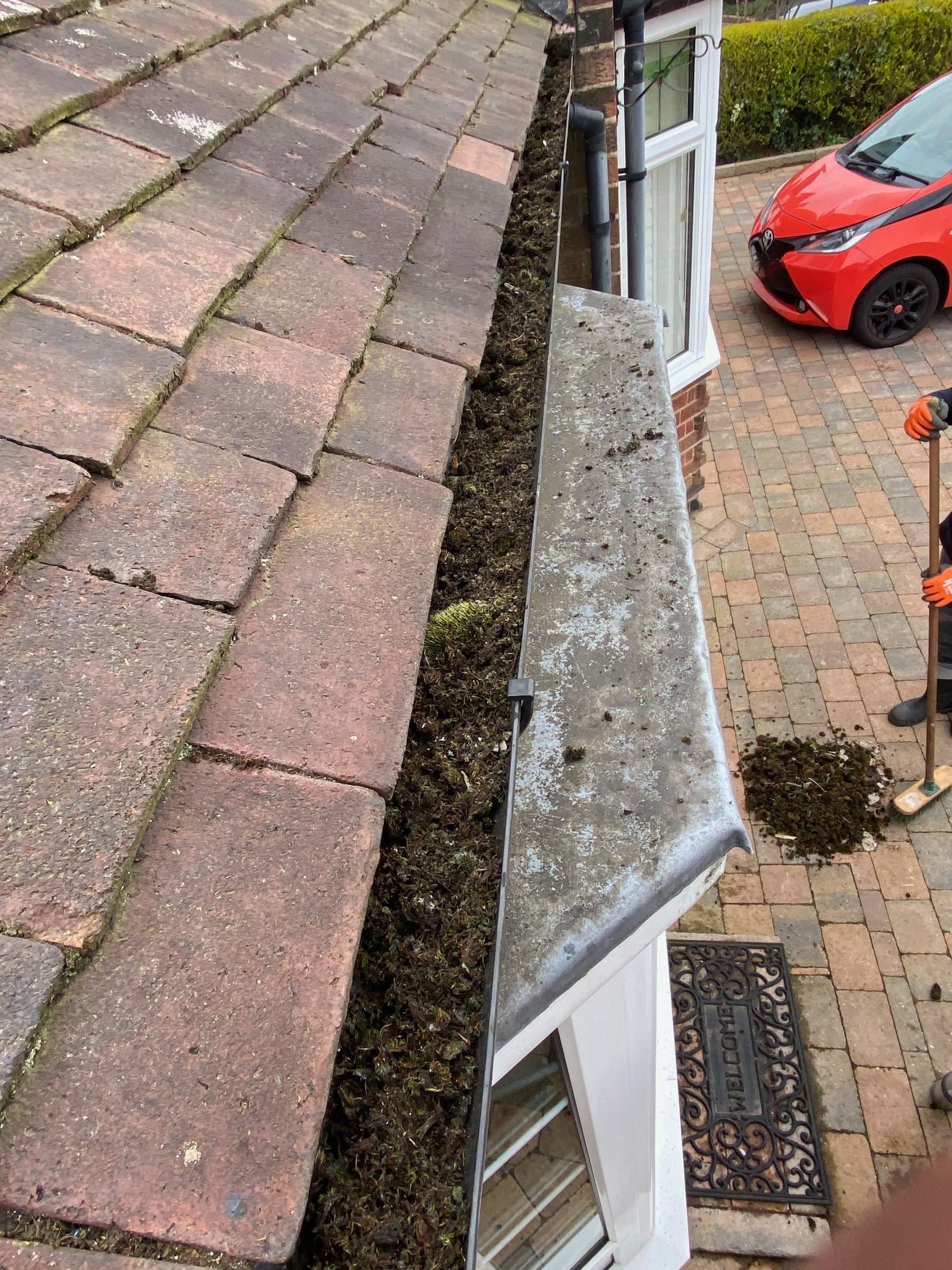 A gutter packed solid with a thick ridge of moss along a red pantile roof