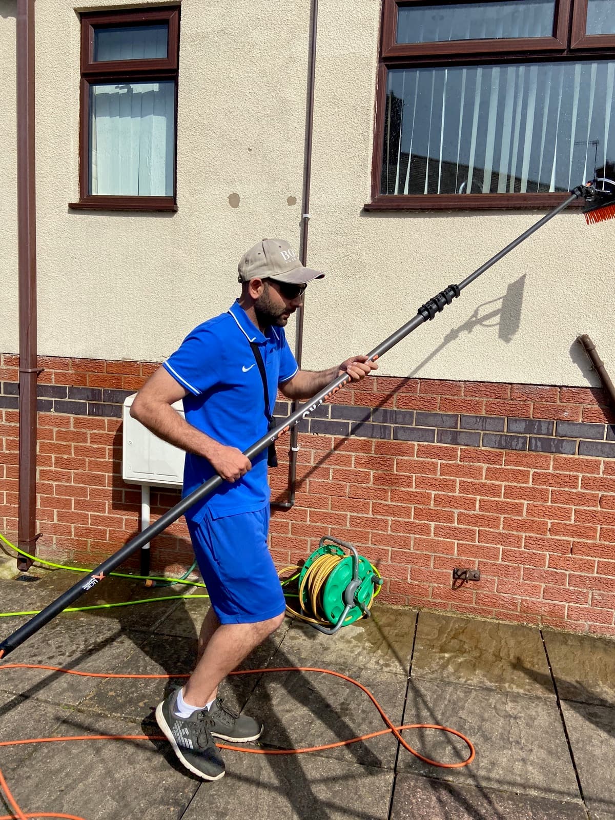 Ace Exterior team member using a water-fed pole to clean upper-floor windows